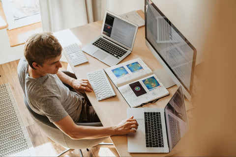 Man Using Three Computers in Home Office